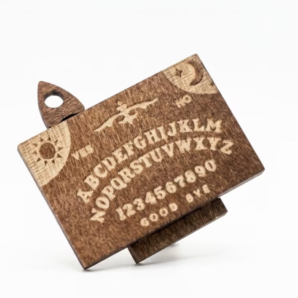 Wooden Ouija board decoration with spooky symbol letters and star cutout handles.