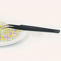 Black pointed craft tweezers next to a bead-filled tray