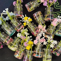 Large resin pot planters with mixed pastel flowers in clear cylindrical pots